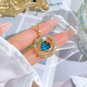 Detail of hand-held gold planet and moon pendant necklace with blue zircon accents
