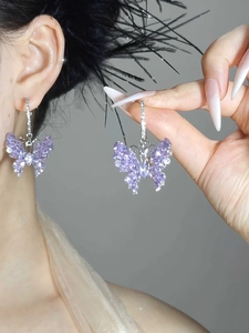 Detail of silver drop earrings featuring sparkling lilac zircon butterfly pendants on a model