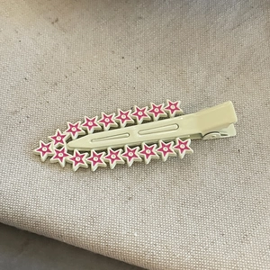 Détail d'une pince à cheveux étoile couleur bonbon avec motifs roses sur base crème