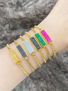 Detail shot of six colorful rectangular gemstone bracelets with gold twisted metal chains