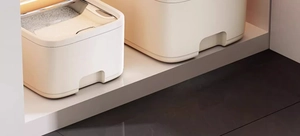 Overhead view of two cream rice storage bins organized inside a warm wooden kitchen cabinet