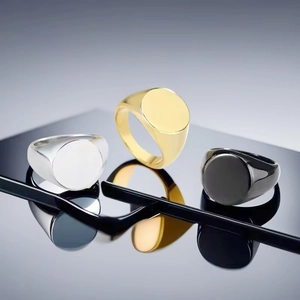 Vista dettagliata di tre anelli a sigillo da uomo minimalisti in argento, oro e nero.
