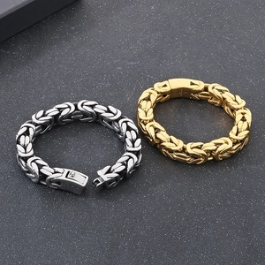 Detailed macro view of gold and silver Byzantine chain bracelets on textured surface