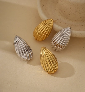 Macro detail of teardrop earrings with vertical stripe texture in gold and silver finish