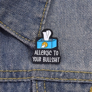 Blue tissue box enamel pin badge with snarky quote on denim background