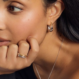 Two-tone geometric earrings and layered ring set in gold and silver finish on model