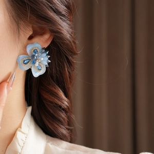 Gros plan détaillé des boucles d'oreilles fleur bleue avec cristaux et perles