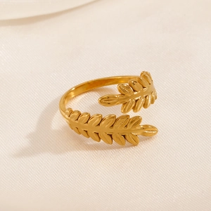 Minimalist gold leaf open ring with olive branch design on beige silk background
