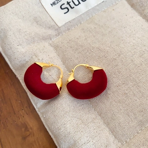 Close-up of vintage red flocked bow pearl earrings on a textured linen pouch