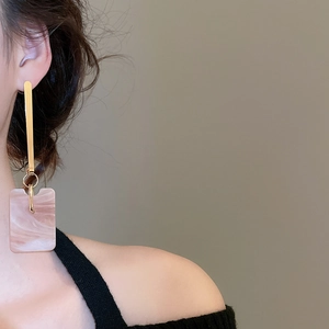 Detail view of pink marble acetate rectangular pendant earrings on model for styling