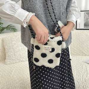 Detailed macro view of soft plush polka dot crossbody bag with woven striped strap