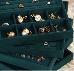 Detail of dark green velvet jewelry trays stacked to show multiple storage compartments