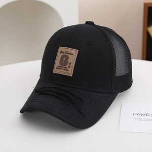 Dettaglio di un cappellino da baseball nero in mesh con tesa sfrangiata e toppa decorativa.