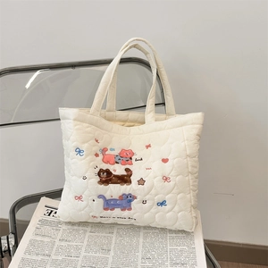 Detail of cute cat embroidery and quilted texture on a white tote bag on a chair