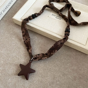 Détail du pendentif étoile vintage en résine avec ruban fleuri et perles en bois