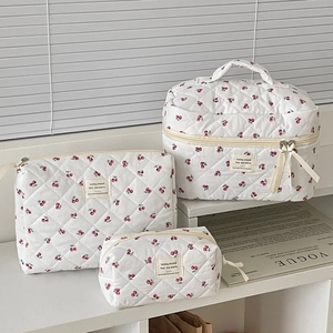 Detailed set of three quilted cherry cosmetic bags with beige ribbon zip pullers