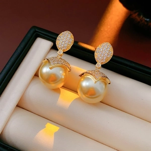 Dettaglio macro di orecchini di perle placcati in oro 18k con zirconi in scatola verde