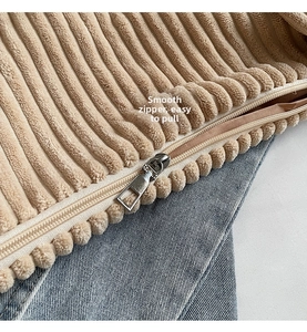 Detail view of the smooth silver zipper and corduroy texture of the beige tote bag