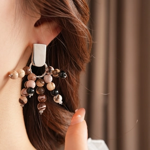 Close-up of vintage beaded earrings with natural stones in pink and brown tones