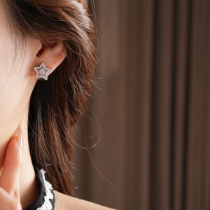 Detailed close-up of model wearing silver star earrings with micro-pave cubic zirconia
