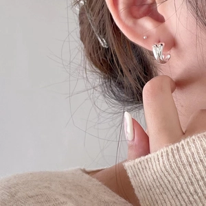 Minimalist 925 sterling silver liquid metal crossover stud earrings worn by a model