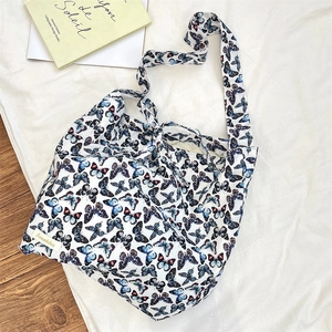 Close-up of butterfly print canvas tote bag with woven brand label on white fabric