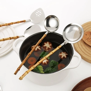 Stainless steel kitchen utensils set with natural bamboo handles displayed over a pot
