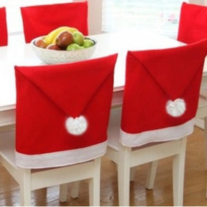 Set of red non-woven Christmas hat chair covers with white pom-poms for festive table decor