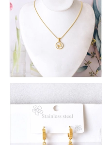 Detail of stainless steel butterfly necklace and gold hoop earrings set on display