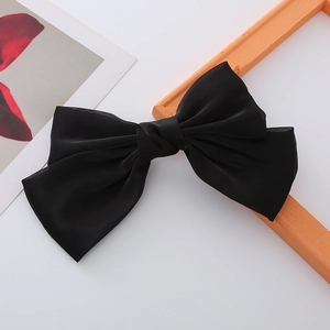 Detail of elegant black double-layered bow hair clip with translucent silk texture