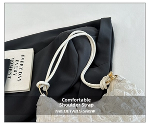 Close-up of the knotted shoulder strap and gold ring hardware on a white pleated bag
