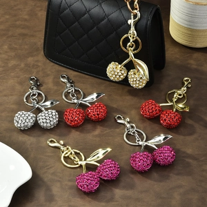 Sparkling rhinestone cherry keychains in multiple colors on a premium leather background
