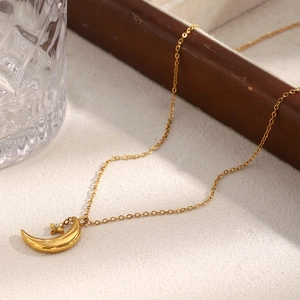 Detail of 18K gold plated moon and star pendant necklace with zircon on a beige surface