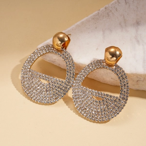 Detailed close-up of golden geometric earrings with micro-pave rhinestones on marble