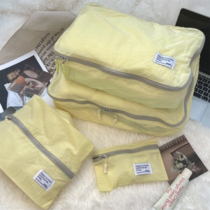 Yellow travel storage organizer set with check pattern texture on a white plush rug