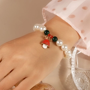 Detail of Christmas beaded bracelet with white pearls, deer horn and red bell charms
