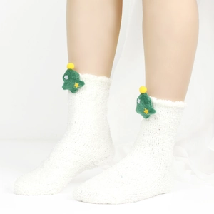 Nahaufnahme von weißen Plüsch-Socken mit grünem Weihnachtsbaum und gelben Sternen