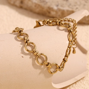 Detail of 14K gold plated stainless steel chain bracelet on a beige ceramic display