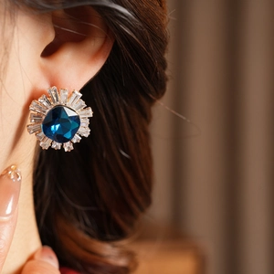 Detailed close-up of a vintage sunflower earring with blue square gemstone and zircons