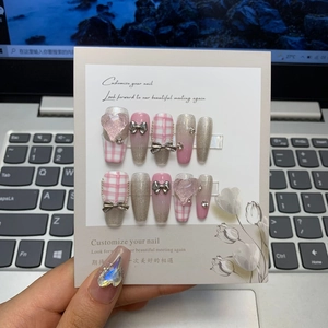 Detail of pink plaid handmade press-on nails with 3D heart and bow decorations