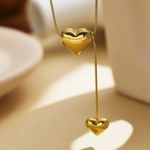 Detail of gold heart pendant necklace featuring double heart charms and elegant fine chain