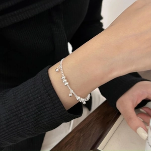 Close-up of 925 sterling silver chain bracelet with small bells and round beads on wrist