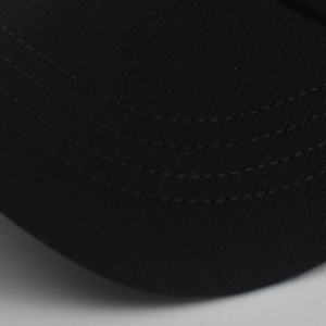Dettaglio della visiera del berretto nero che mostra il tessuto in twill e le cuciture parallele