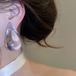Detailed close-up view of minimalist transparent acrylic water drop earrings on model