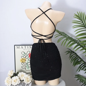 Detail eines schwarzen Zweiteilers mit Pailletten-Halter-Top und figurbetontem Minirock