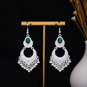 Close-up of silver boho earrings with green stones and hanging tassel details