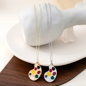 Detail of artistic palette pendants with colorful enamel on gold and silver chain necklaces