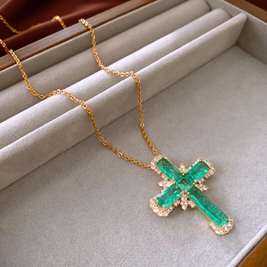 Détail d'un pendentif croix dorée avec pierres vert émeraude et pavé de diamants en boîte