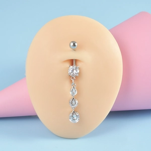 Macro view of silver heart navel ring with teardrop zircons on a soft silicone belly model