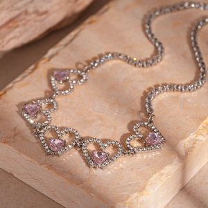 Macro shot of silver necklace featuring pink heart zircons and pavé-set diamond details